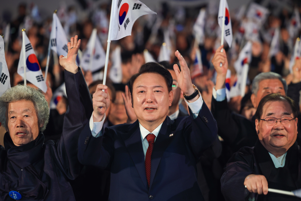 President Yoon Suk Yeol (center, front) waves the national flag during a ceremony in remembrance of the March 1st Independence Movement, at the Yu Gwan-sun Memorial Hall in Seoul, Friday. (Presidential Office)