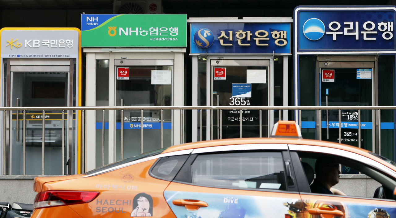 A taxi passes by ATMs of major local banks lined up on a Seoul street. (Newsis)