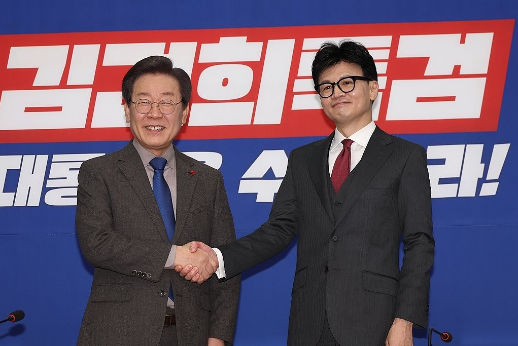 Democratic Party of Korea Chair Lee Jae-myung, left, shakes hands with People Power Party Interim Chair Han Dong-hoon at the main opposition headquarters in western Seoul in December last year. (Yonhap)