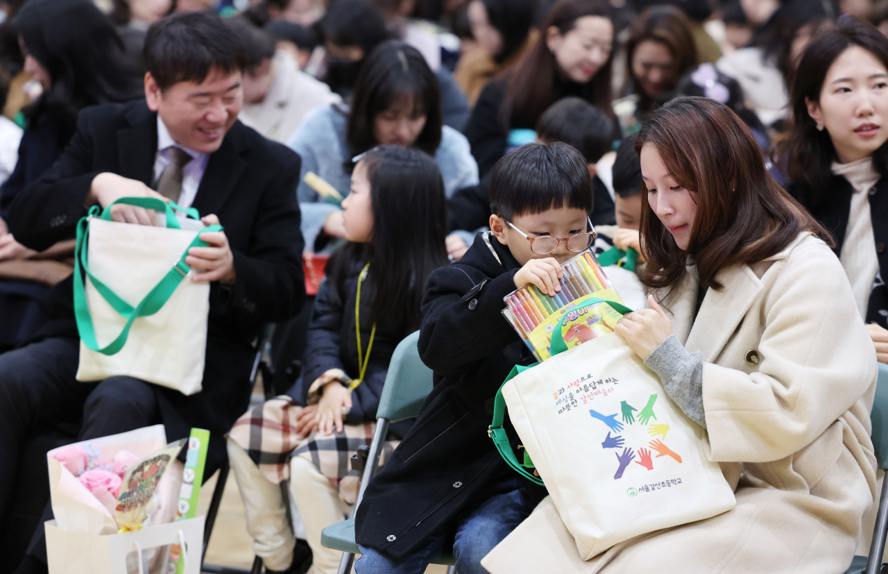 A child and his mom look inside a bag consisting of gifts at an entrance ceremony in Galsan Elementary School, Monday. (Yonhap)