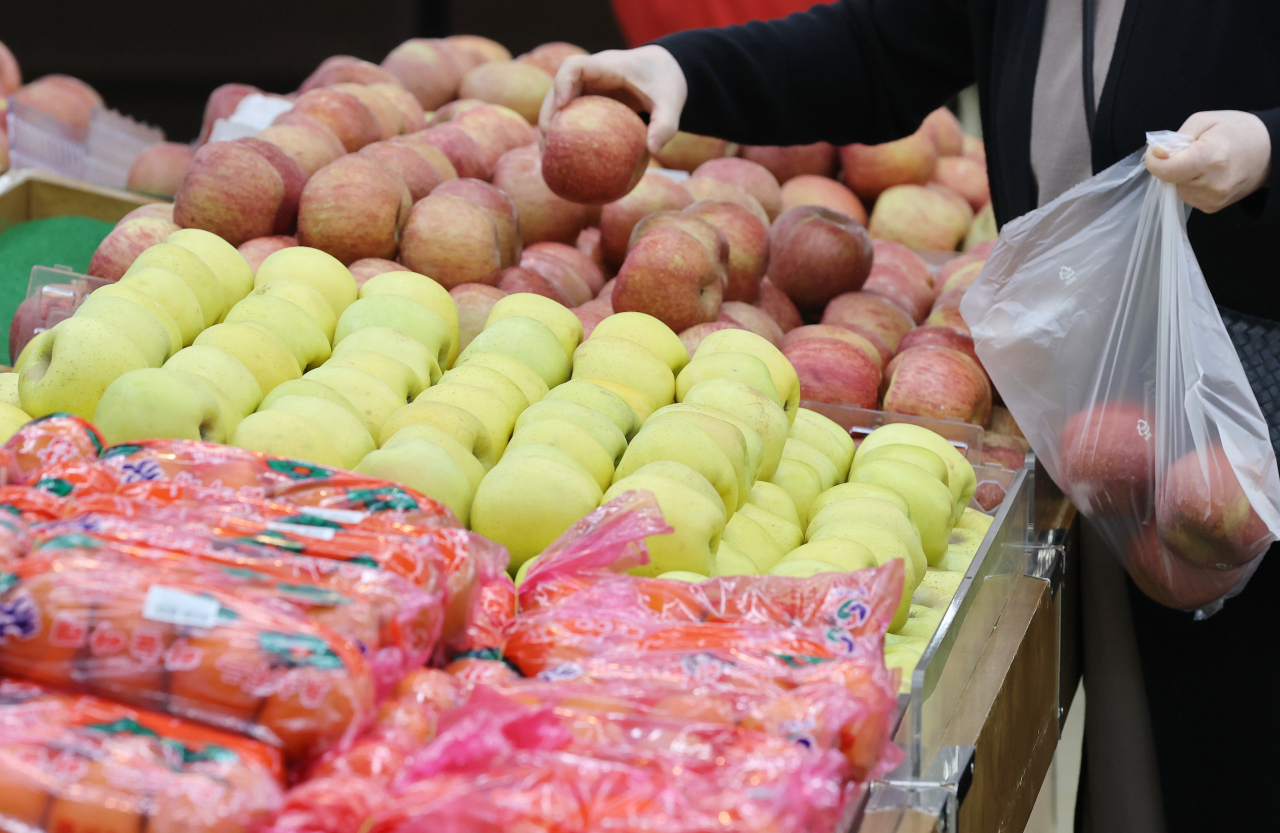 A customer picks up apples at a supermarket in Seoul, on Thursday. (Yonhap)