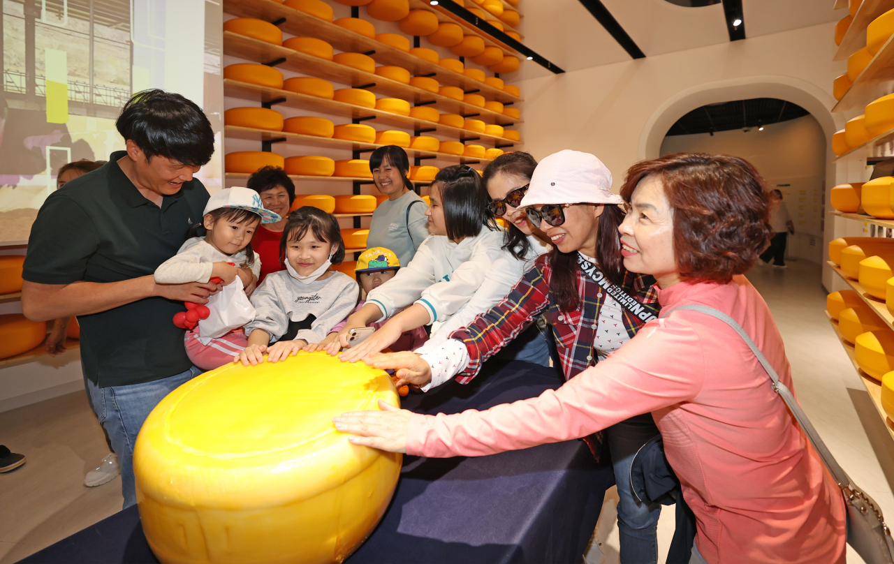Tourists touch a 50-kilogram giant cheese wheel exhibited at the ninth Imsil N Cheese Festival held in 2023 (Imsil-gun)