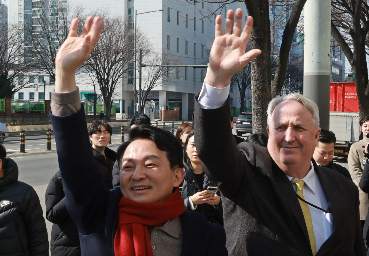 Won Hee-ryong (left), the former land and transport minister for President Yoon Suk Yeol, and Yohan Ihn, the former chief of the ruling People Power Party’s reform committee, wave to residents of Incheon near Seoul on Feb. 26. Won is running for office in the Incheon district against Rep. Lee Jae-myung, the Democratic Party of Korea chief and onetime presidential candidate. (Yonhap)