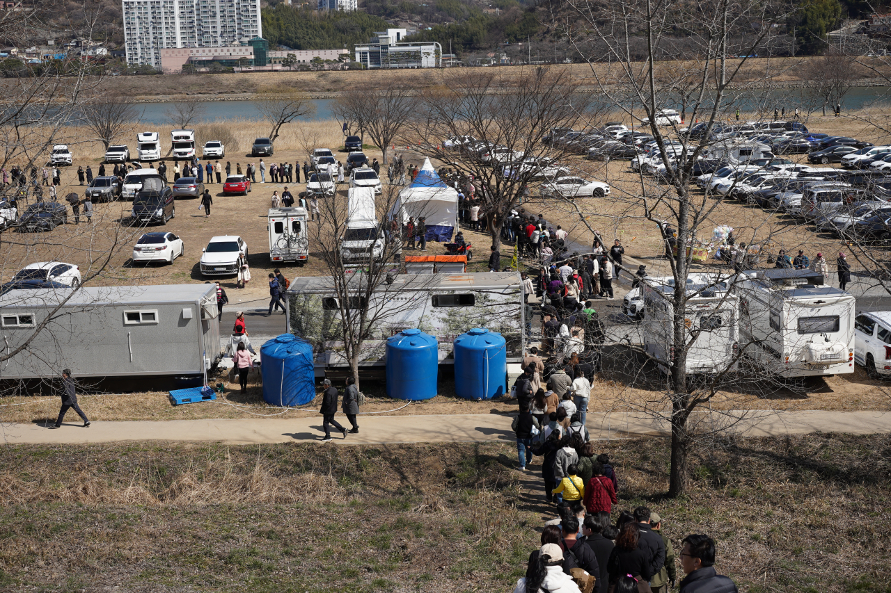 Tourists wait in a seemingly endless line for the shuttle bus at Dunchi parking lot in Gwangyang, South Jeolla Province, on Saturday. (Lee Si-jin/The Korea Herald)