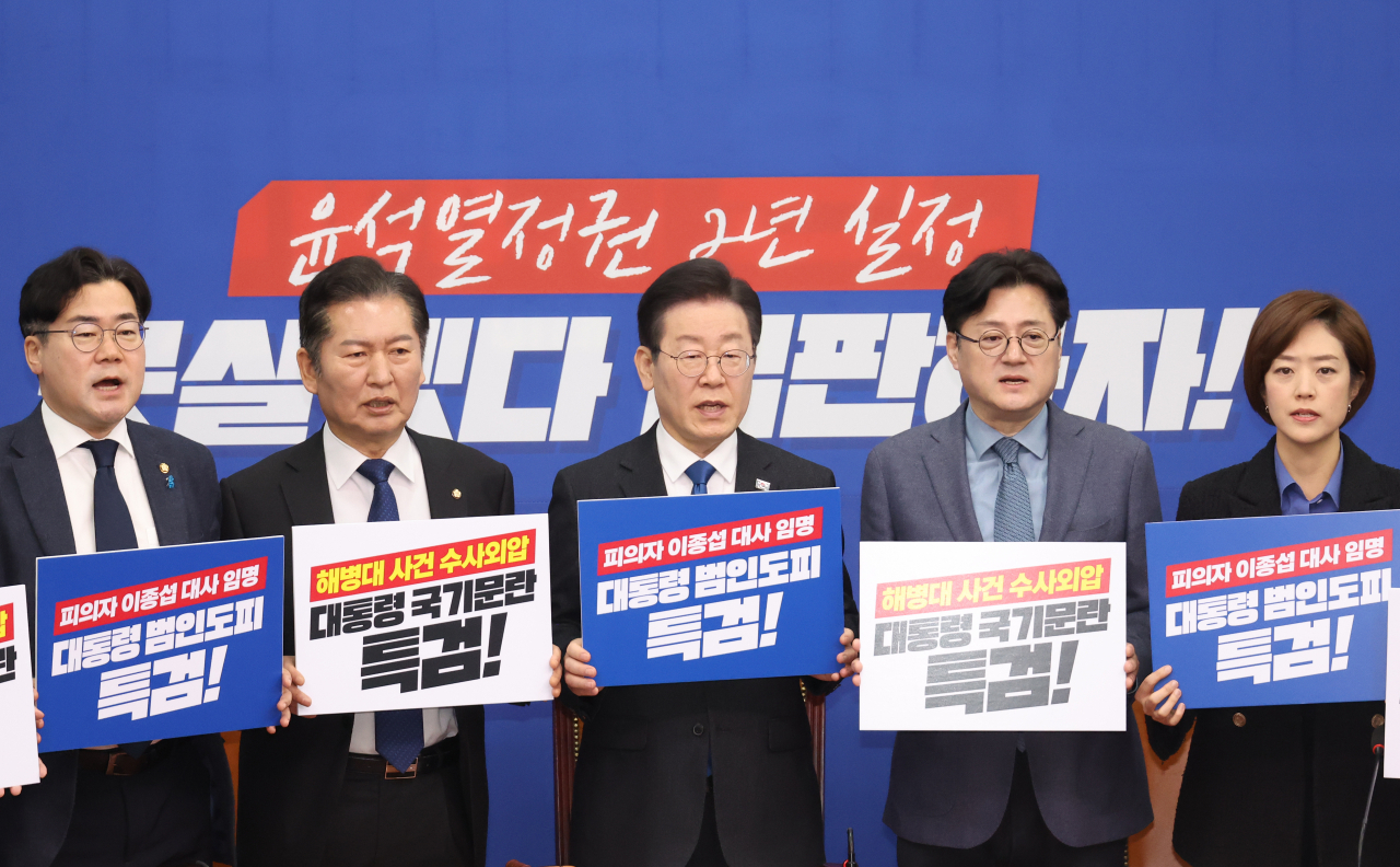 Democratic Party of Korea Chair Lee Jae-myung, center, and Democratic Party Floor Leader Hong Ihk-pyo, second from right, holds signs protesting the Yoon Suk-yeol administration's decision to lift former Defense Minister Lee Jong-sup's travel ban, at the National Assembly in Seoul on Monday. (Yonhap)