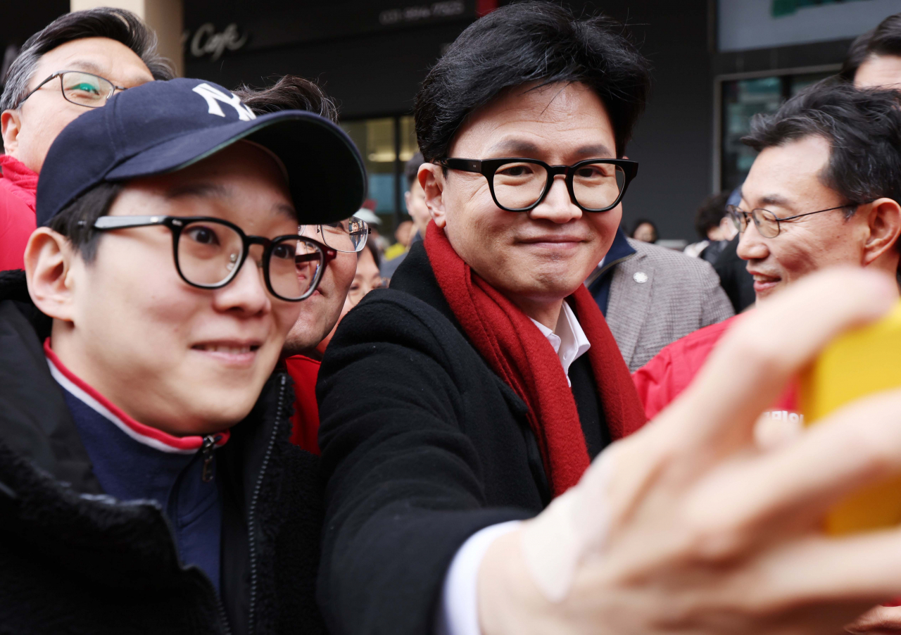 Han Dong-hoon (right), interim leader of the ruling People Power Party, takes a selfie with supporters during a visit to a mall in Ilsan, Gyeonggi Province, near Seoul on Monday. (Yonhap)