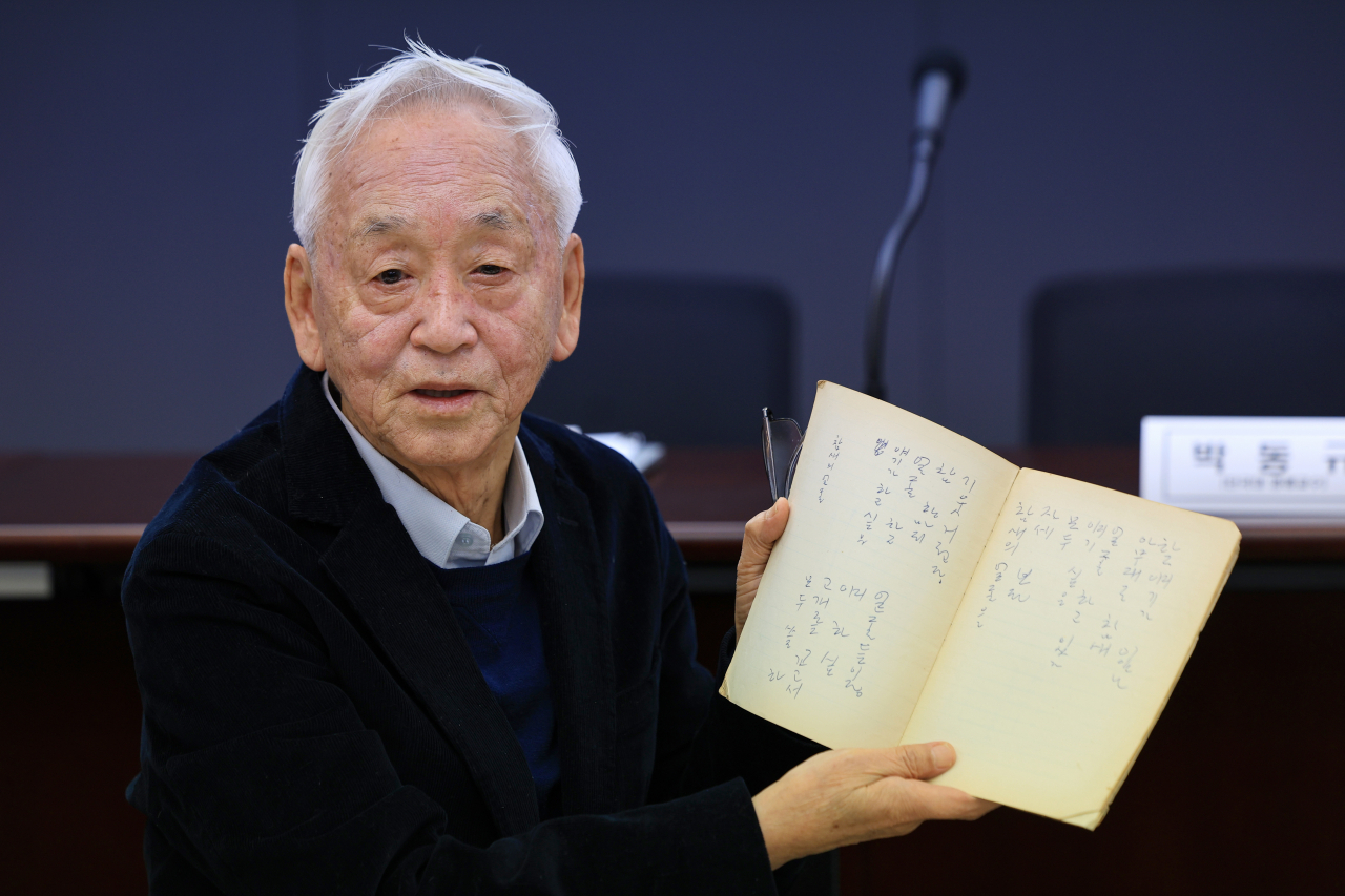 Park Dong-gyu holds up one of the notebooks of his father, the late poet Park Mok-wol, during a press conference in Seoul on Tuesday. (Yonhap)