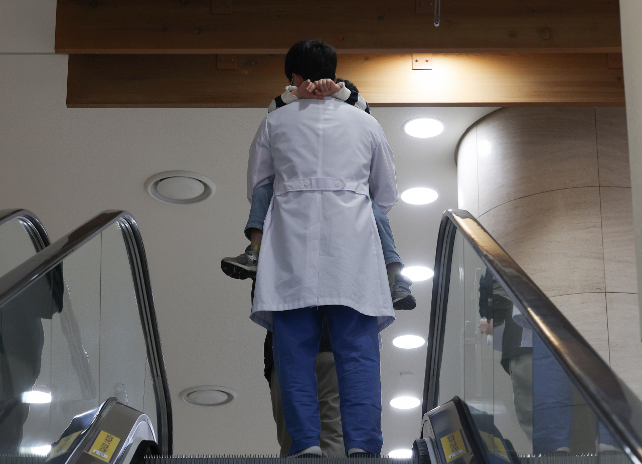 A medical worker goes up the escalator holding a child (Yonhap)
