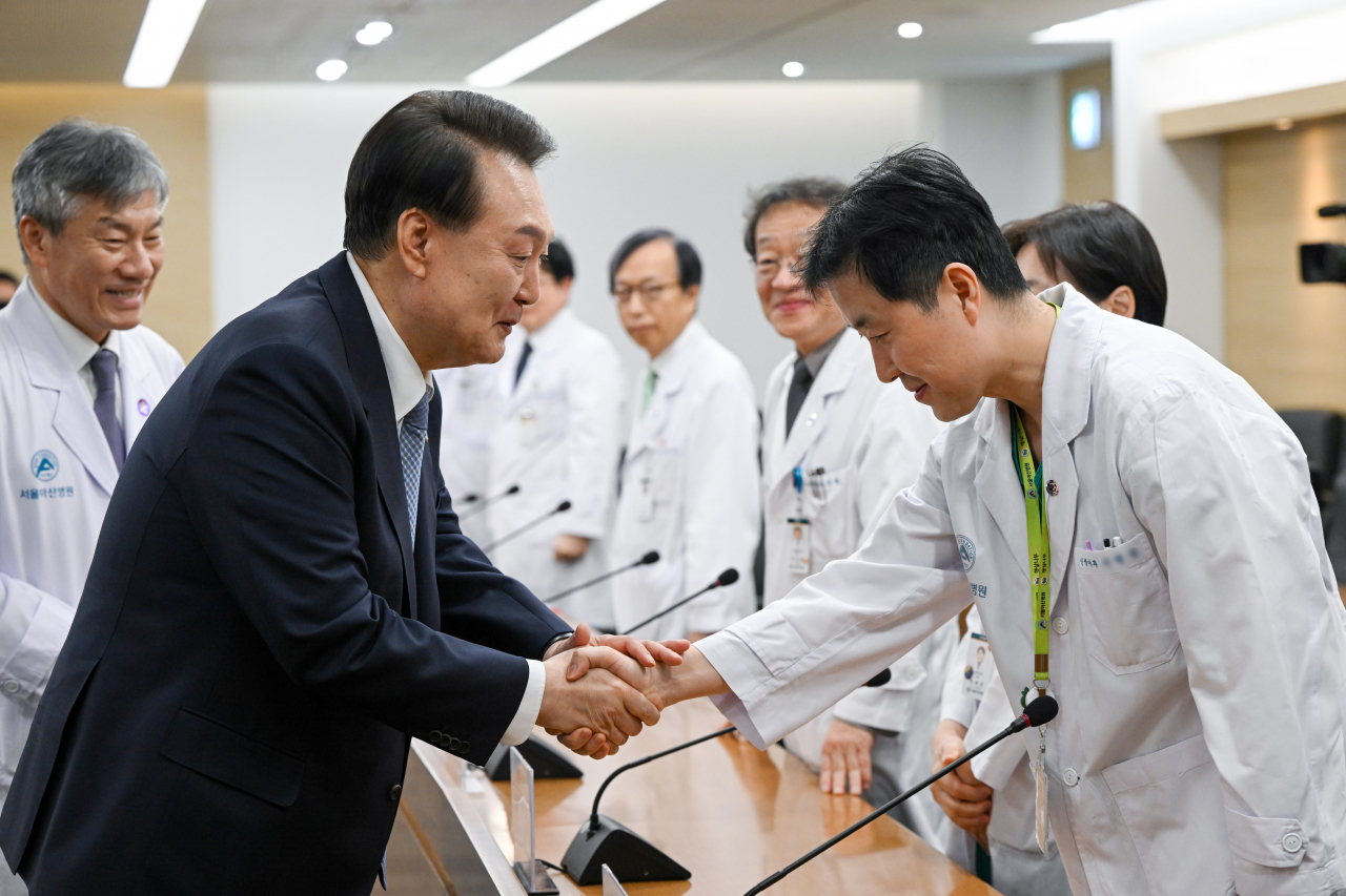 President Yoon Suk Yeol (second from left) shakes hands with a doctor at Asan Medical Center in Seoul, Monday (Presidential Office)