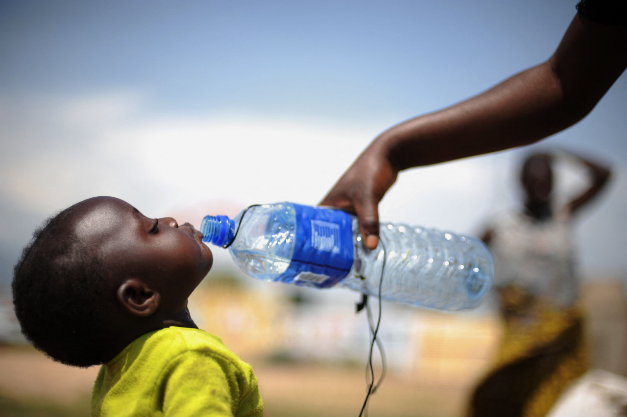 This file photo shows a toddler getting a drink water from her mother as they and a dozen other residents of the North Kivu town of Nyanzale gather in front of a UN peacekeepers base in the town of Rwindi, Congo, Nov. 19, 2008. (AFP-Yonhap)