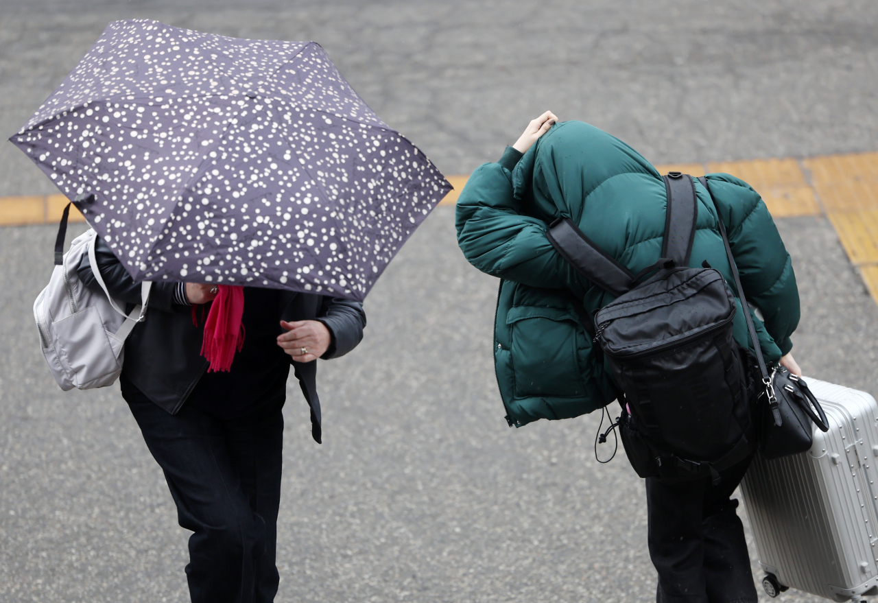 Passersby walk in the rain in front of Seoul Station on Tuesday. (Yonhap)