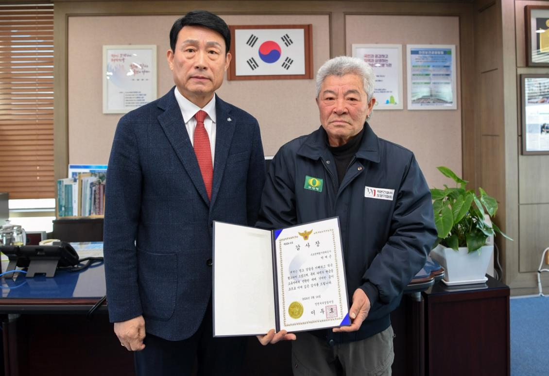 Park Jae-geun (right) poses Wednesday after being awarded a prize from Incheon Seobu Police Station at the office of Sudokwon Landfill Site Management Corp. in Incheon. (SLC)
