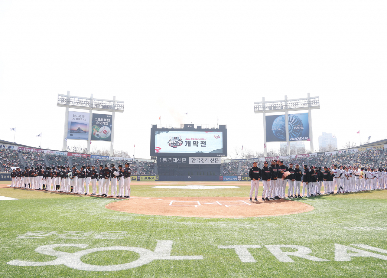 Players for the Hanwha Eagles (left) and the LG Twins stand on the field at Jamsil Baseball Stadium in Seoul before their Korea Baseball Organization Opening Day game on Saturday. (Yonhap)