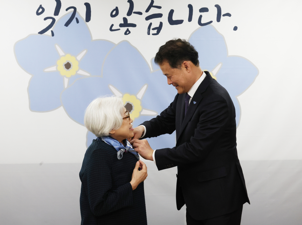 South Korean Unification Minister Kim Yung-ho (right) attaches a forget-me-not badge to Lee Mi-il, former president of the Korean War Abductees Family Union, whose father was abducted by North Korea in September 1950, during an event Wednesday at the government complex building. (Yonhap)