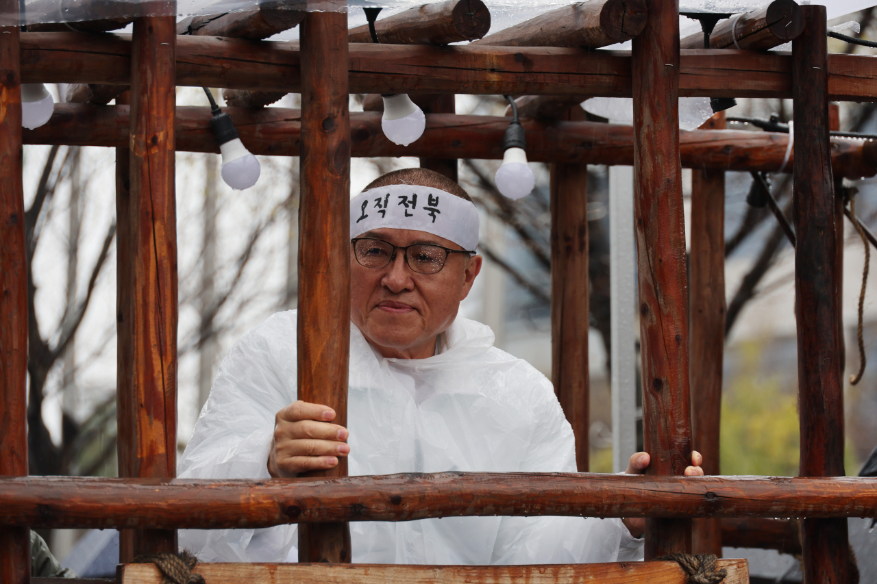 Rep. Chung Woon-chun shaved his head and locked himself inside a wooden cage cart as he kicked off his official campaigning in Jeonju, North Jeolla Province on Thursday. (Yonhap)
