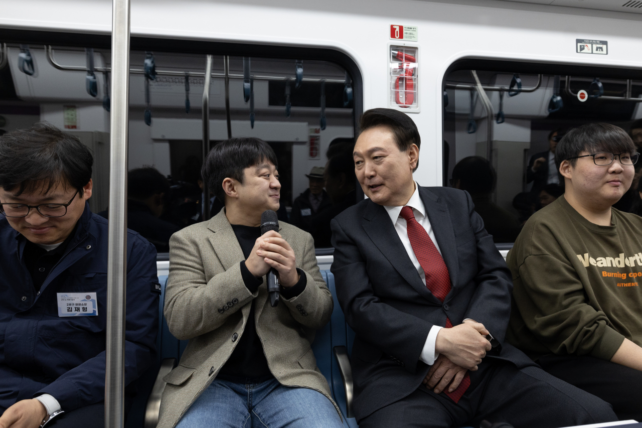 President Yoon Suk Yeol (second from right) is seen having a conversation with a citizen as they were aboard a GTX-A train on a test run from Suseo Station in southern Seoul to Dongtan in Hwaseong, Gyeonggi Province, on Friday,