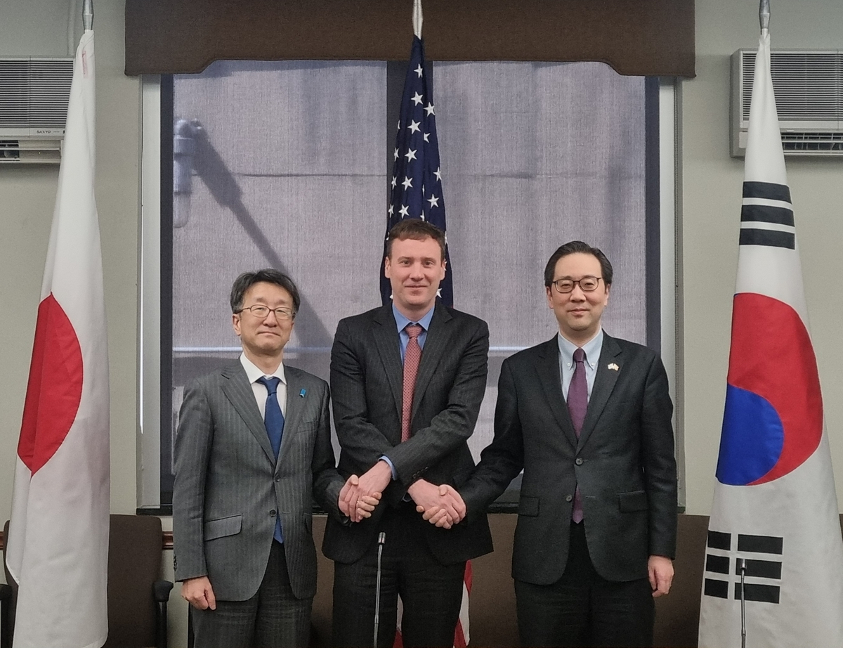Lee Jun-il (right), director general for North Korean nuclear affairs at the Foreign Affairs Ministry, and US and Japanese representatives, Lyn Debevoise (center) and Naoki Kumagai, respectively, pose for a photo as they meet for the second session of a trilateral working group on North Korean cyberthreats in Washington, D.C., Friday. (Ministry of Foreign Affairs)