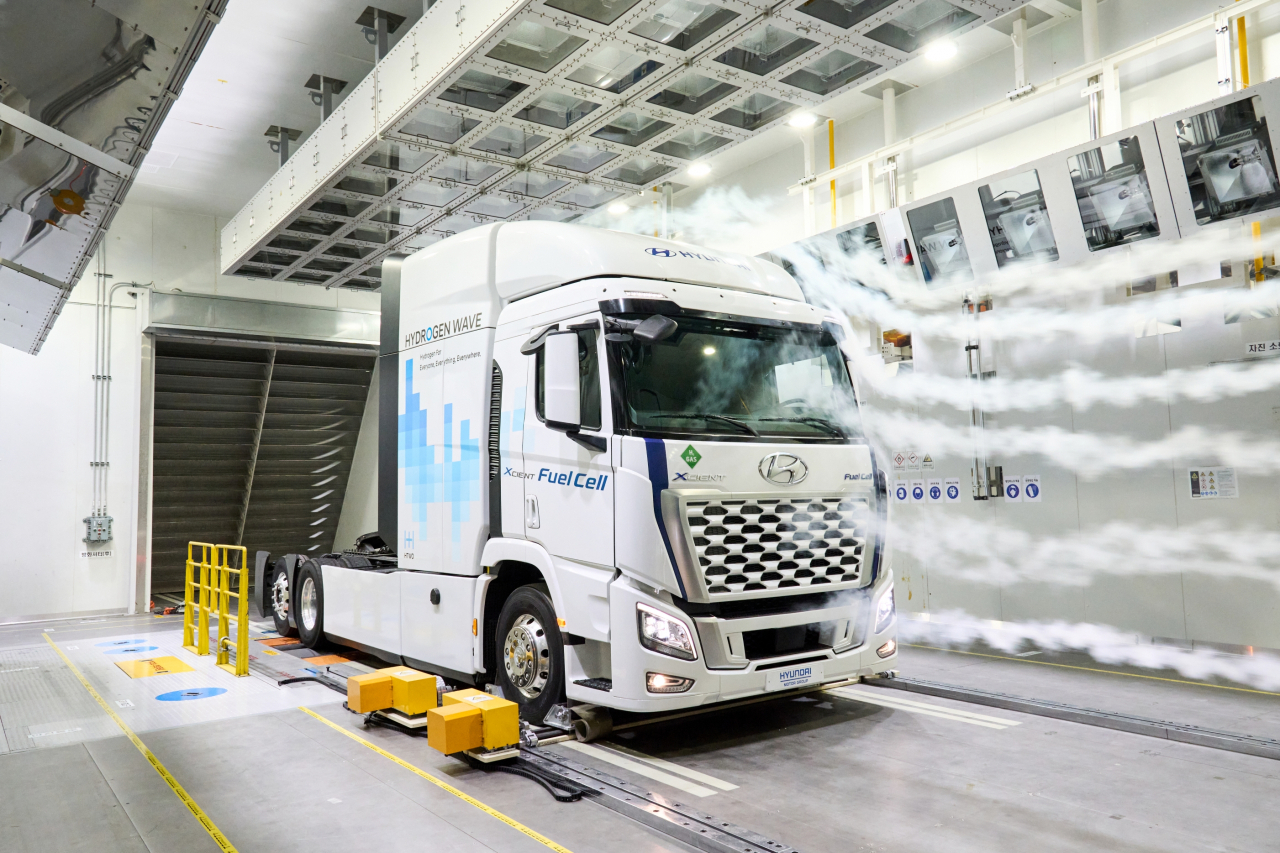 A Hyundai Xcient hydrogen-electric truck is engaged in aerodynamic testing in the chamber, with visible smoke illuminating the airflow patterns around the vehicle to help engineers optimize its design for improved efficiency. (Hyundai Motor Group)