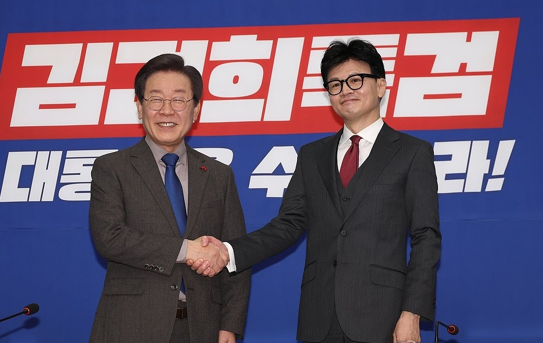 Democratic Party of Korea leader Lee Jae-myung (left) and People Power Party Interim Chair Han Dong-hoon shake hands at the National Assembly in western Seoul in December last year. (Yonhap)
