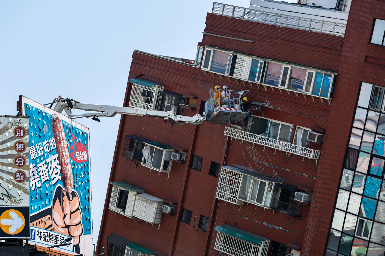 Workers carry out operations while on an elevated platform of a firefighting truck at the site of a collapsed building, following an earthquake in Hualien, Taiwan, Thursday. (Reuters-Yonhap)