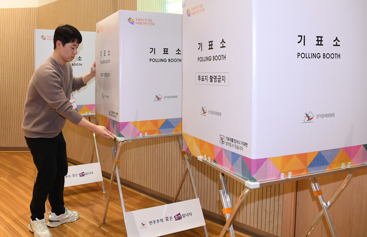 A volunteer helps set up a polling booth for early voting for the April 10 general election, in this photo taken at a local community service center in central Seoul on Thursday. (Yonhap)
