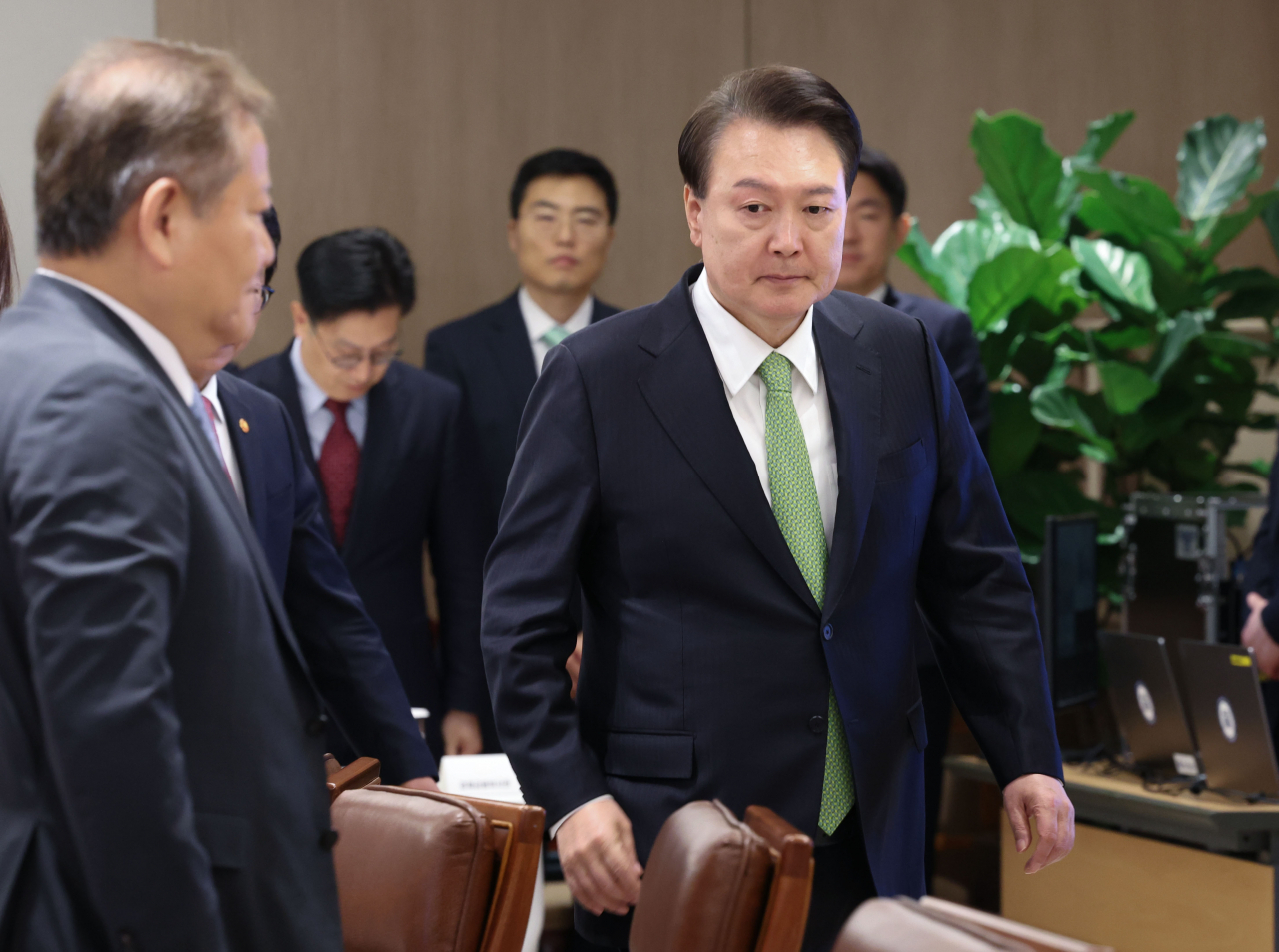 President Yoon Suk Yeol (right, wearing a light green tie) enters a meeting room in his office in Seoul as he presided over the meeting to monitor the nation's housing supply on Monday. (Yonhap)