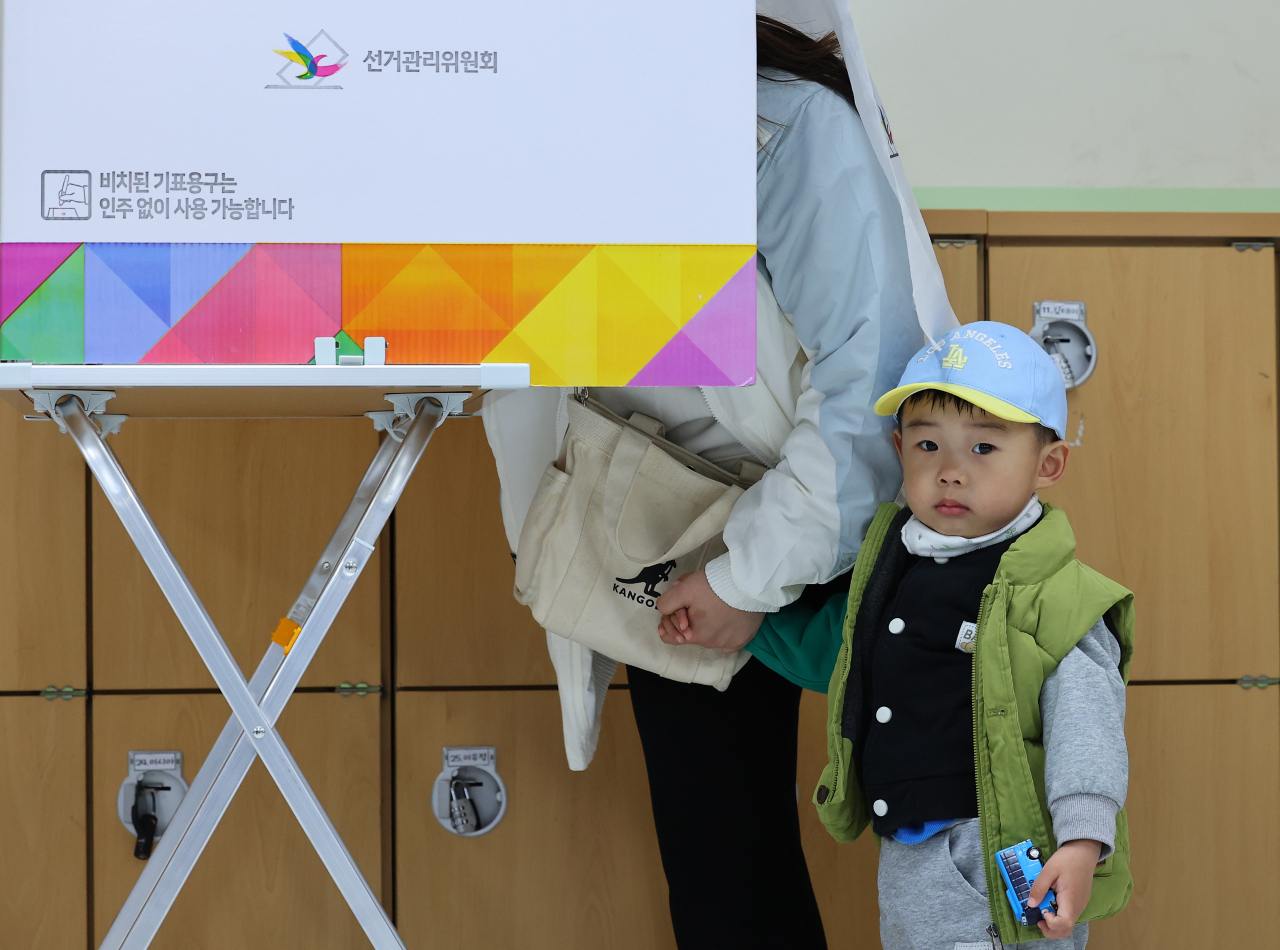 A child is seen accompanying his mother casting a ballot at a polling station on Wednesday. (Yonhap)