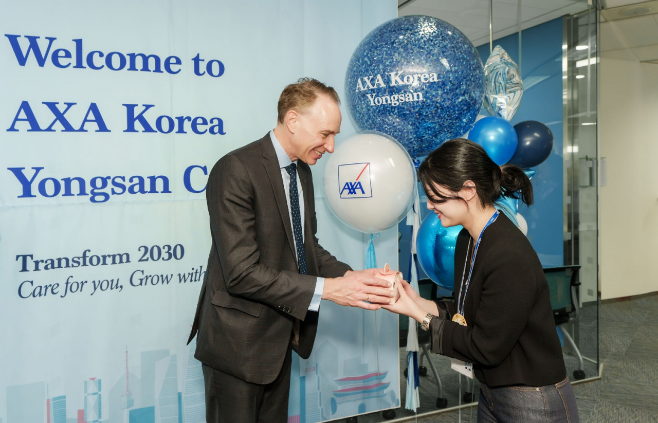 AXA CEO Thomas Buberl (let) presents a gift to an employee during his visit to AXA Korea in Yongsan-gu, Seoul, on Tuesday. (AXA Korea)