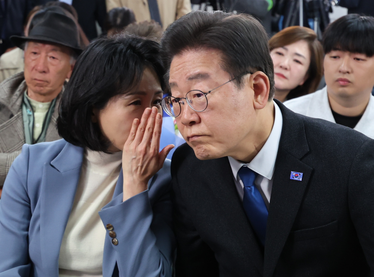 Democratic Party of Korea Chair Lee Jae-myung (right) speaks with his wife, Kim Hye-kyung while watching the TV broadcast for the results of Wednesday's general election at his office in Incheon on Thursday morning. (Yonhap)