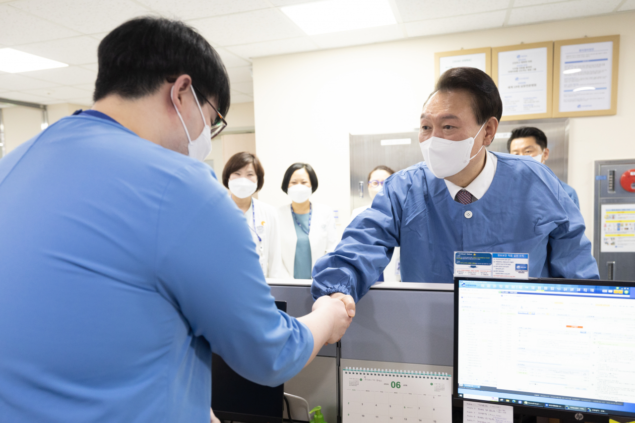 President Yoon Suk Yeol (right) shakes hands with a medical professional as he visits a secondary hospital in Bucheon, Gyeonggi Province, on Tuesday. (Presidential Office)