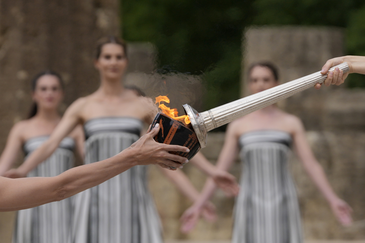 Torch gets lighted during the official ceremony of the flame lighting for the Paris Olympics, at the Ancient Olympia site, Greece, Tuesday. (AP-Yonhap)
