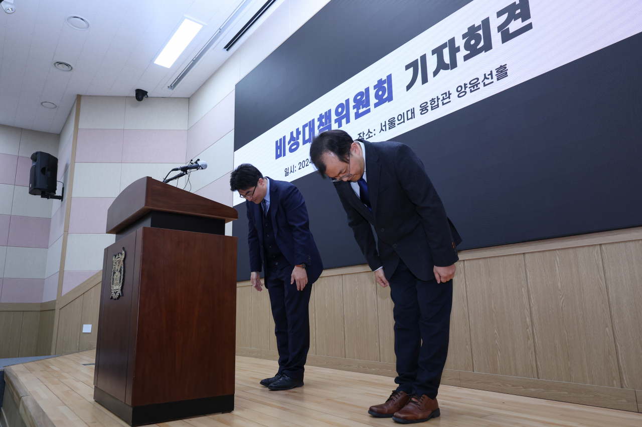 Bang Jae-seung (left), the head of the emergency response committee of medical professors at Seoul National University and Seoul National University Hospital, and Bae Woo-kyung, who heads the emergency committee’s public relations council, bow after giving their statements during a press conference held at SNU in Jongno-gu, central Seoul, Wednesday. (Yonhap)