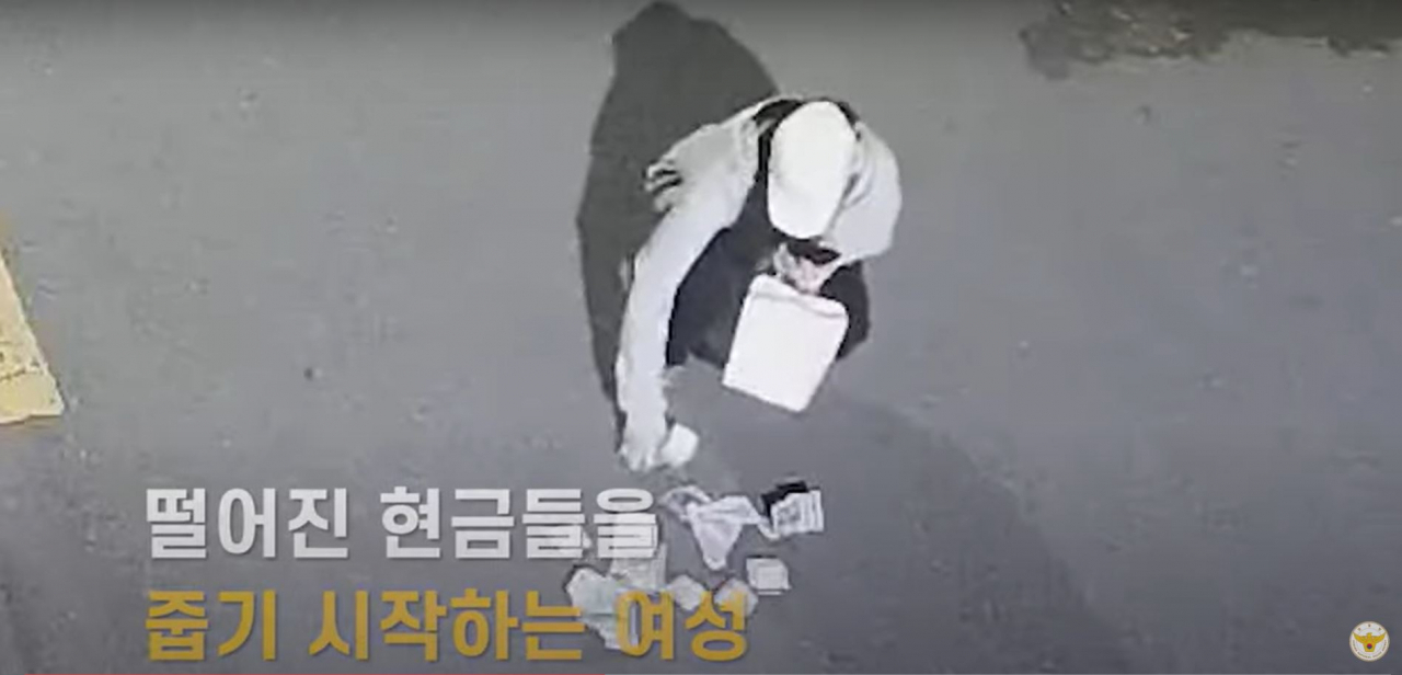 Footage shared by the National Police Agency shows a high school girl picking up cash that was dropped earlier by a man, at Hadong-gun, South Gyeongsang Province, Feb.27. (National Police Agency’s YouTube)