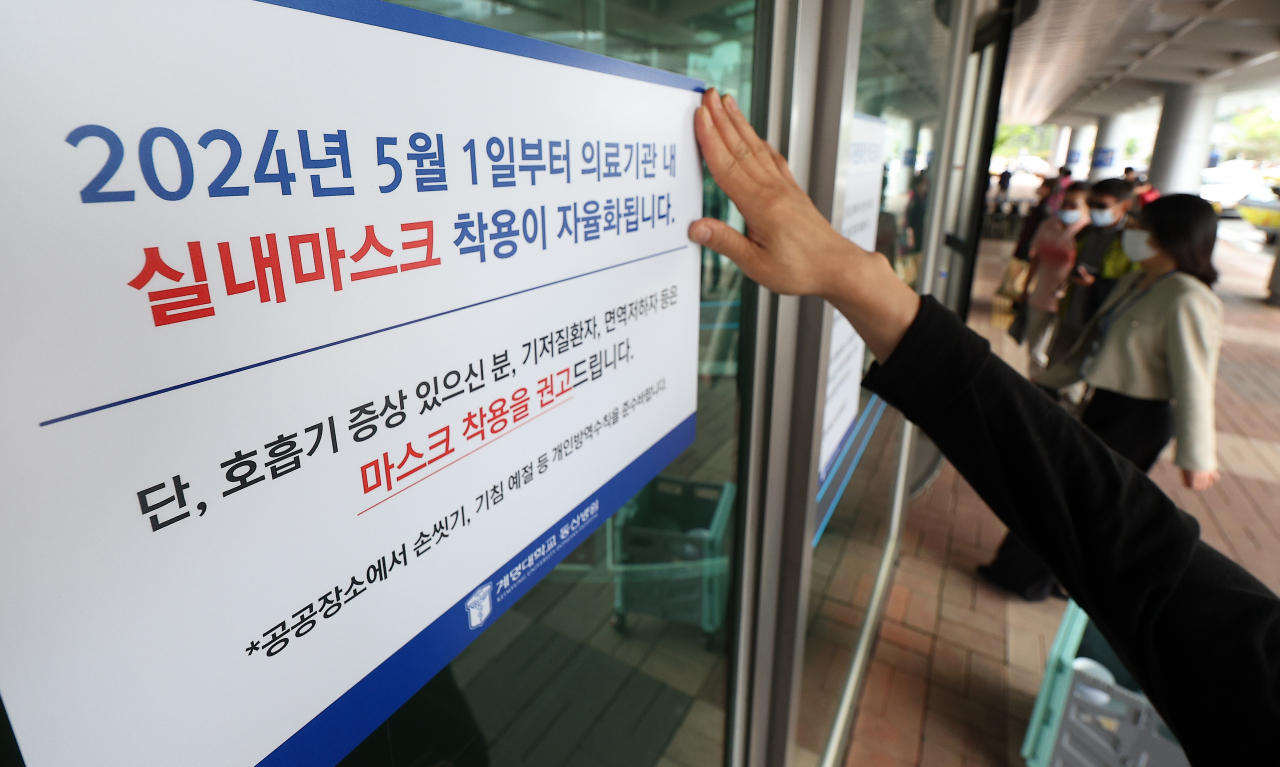 An official puts up a notice at a hospital in the southeastern city of Daegu on Tuesday, informing people of the lifting of indoor mandatory mask wearing at hospitals starting Wednesday.