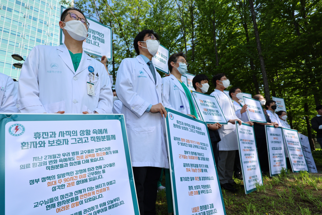 Medical professors at the Asan Medical Center in Songpa-gu, southern Seoul, stage a protest in front of the hospital on Friday to condemn the government’s decision to have more medical students starting next year. (Yonhap)