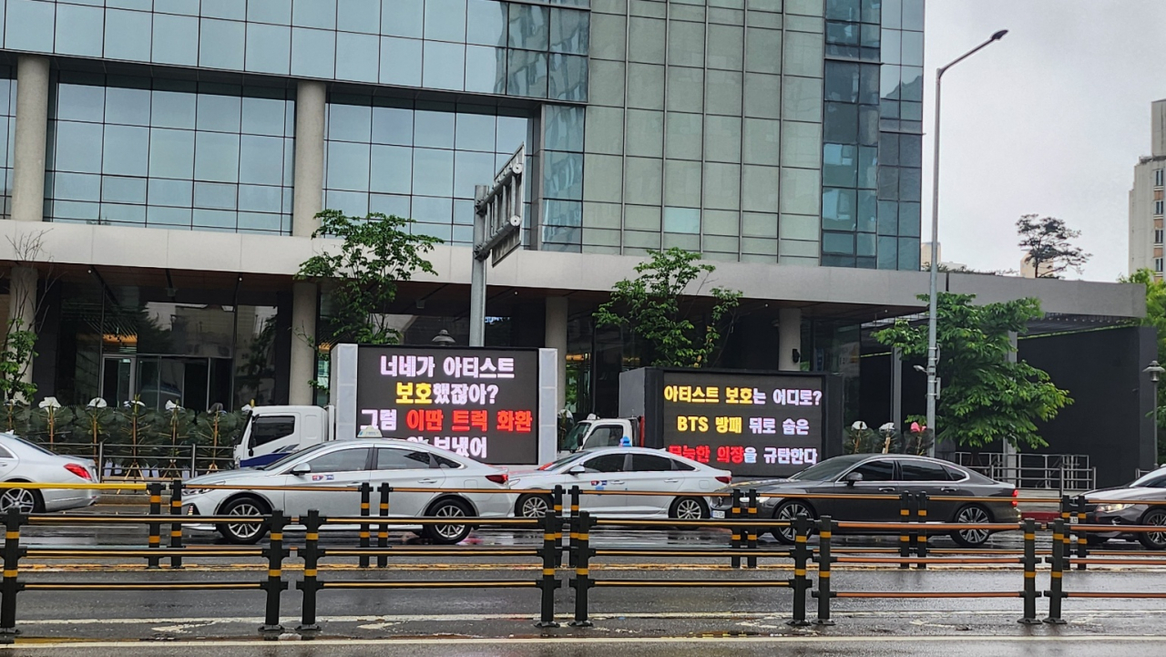 Trucks with large electronic display boards and protesting messages are parked in front of the Hybe's headquarters in Yongsan-gu, Seoul, Monday. (Lee Jung-youn/The Korea Herald)