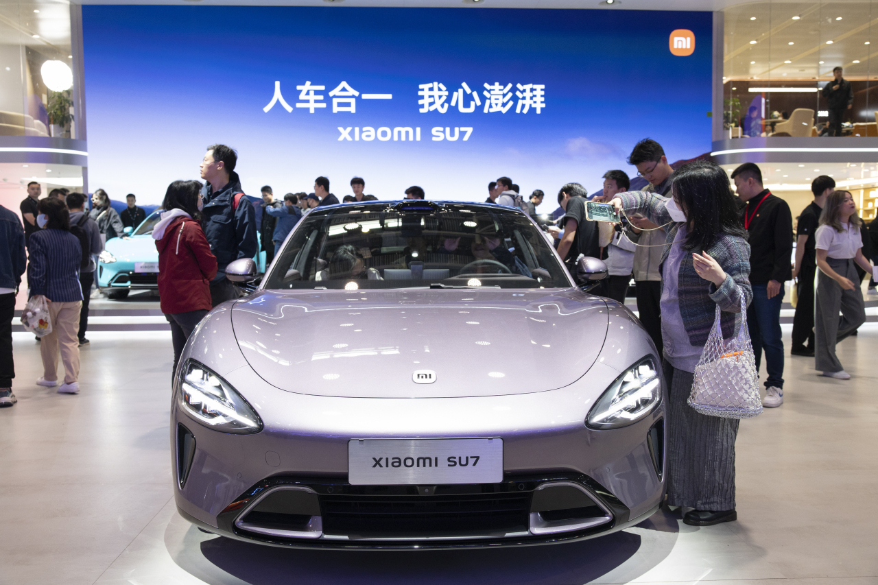 A visitor takes a picture of a Xiaomi SU7 at the 2024 Beijing International Automotive Exhibition in Beijing, Apr.29.