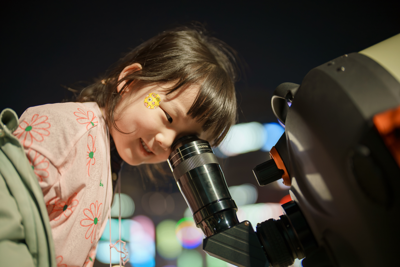 A girl observes Jupiter through a telescope in a park in Ilsan, northwest of Seoul, in March. (Source: Hong Kee-cheon)