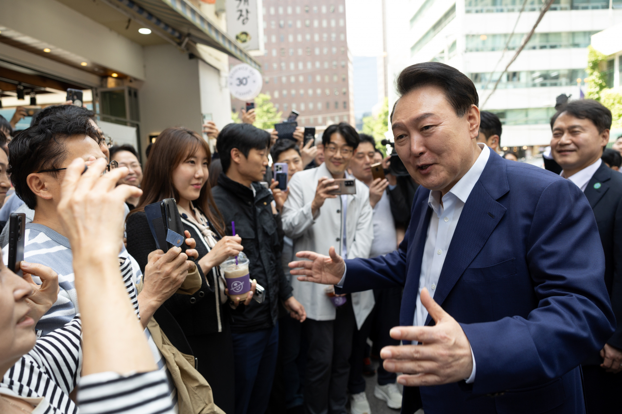 President Yoon Suk Yeol (right) is seen surrounded by a crowd on a street near the Cheeonggyecheon in Seoul on Friday. (Presidential Office)