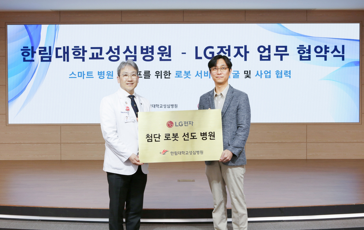 Noh Gyu-chan, head of LG Electronics' robot unit (right) and Yu Kyung-ho, the director of the Hanllym University Sacred Heart Hospital, pose at a signing ceremony in Seoul on Friday. (LG Electronics)
