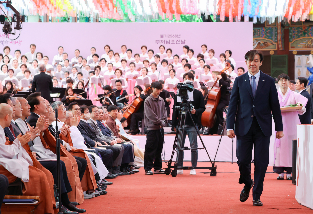 Cho Kuk, the leader of the Rebuilding Korea Party, walks in front of President Yoon Suk Yeol during a celebration event held at the Jogye Temple in central Seoul on Wednesday. (Yonhap)