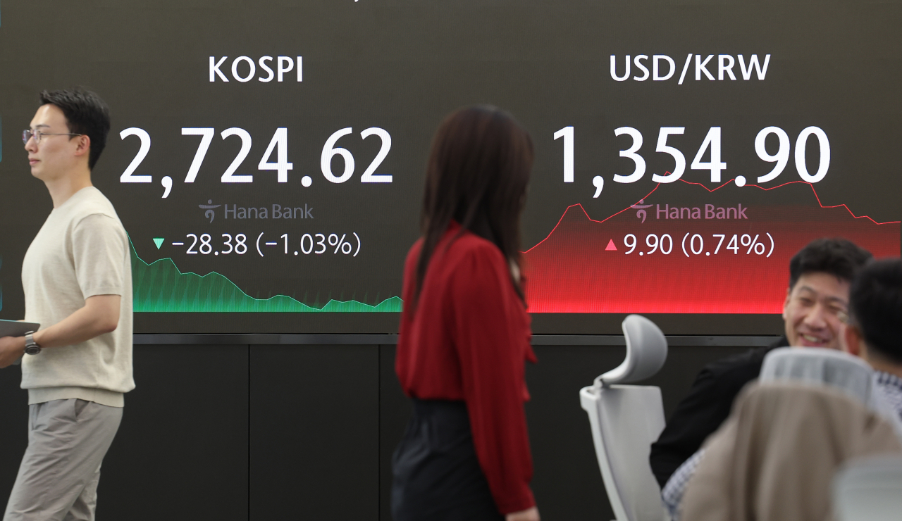 Dealers are seen working at a dealing room of the Hana Bank headquarters in Seoul, in front of electronic boards showing the Korean Composite Stock Price Index and the Korean won-US dollar exchange rate, on Friday. (Yonhap)