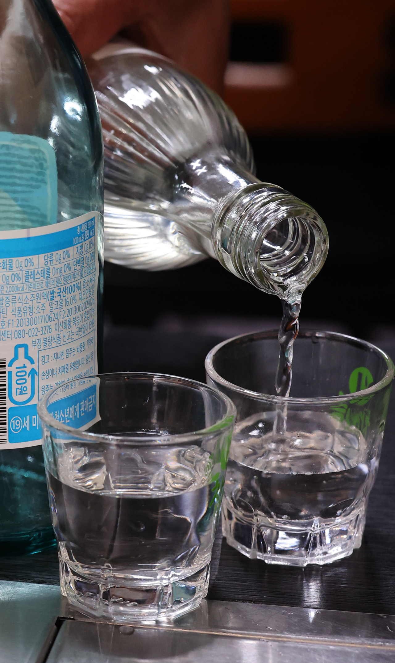 A person pours soju into a glass at a Seoul restaurant. (Newsis)