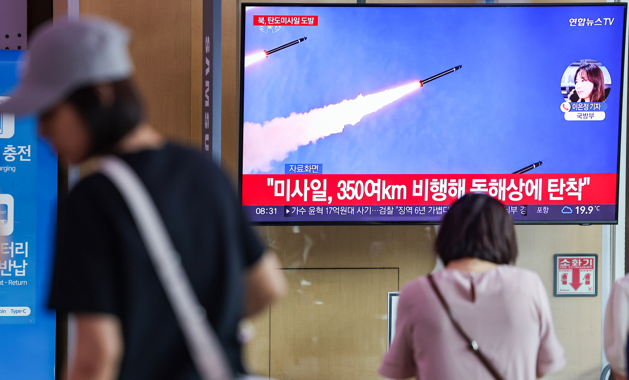 Pedestrians are seen in front of a screen showing a news report about North Korea's test-firing of what South Korean military believes were short-range ballistic missiles at Seoul Station in Seoul on Thursday. (Yonhap)