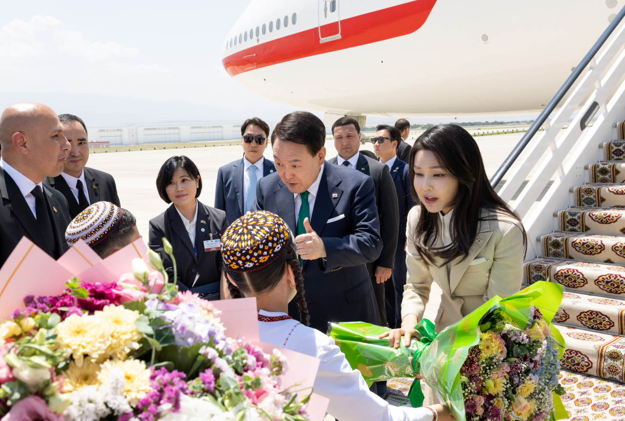 President Yoon Suk Yeol (second from right, front row) and first lady Kim Keon Hee (right, front row) receive bouquets of flowers from children as they disembarked on the Air Force One at Ashgabat International Airport in Ashgabat, Turkmenistan, on Monday. (Pool photo via Yonhap)
