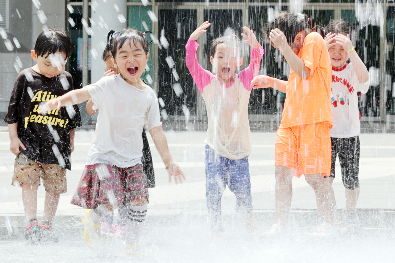 Children run through a water fountain in Gwangju, where daytime temperatures are expected to reach as high as 32 degrees Celsius. (Yonhap)