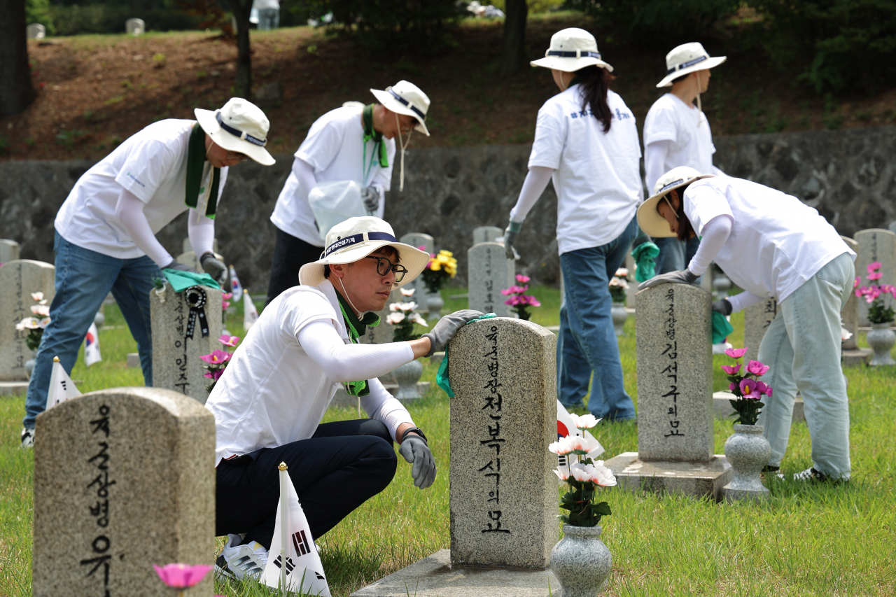 A group of HD Hyundai employees engaged in cleaning and maintaining graves at Seoul National Cemetery last Friday to commemorate the Korean Patriots and Veterans month of June (HD Hyundai)