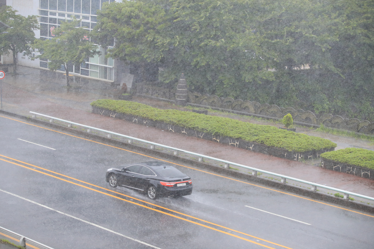 A car splashes rain through a street in Seogwipo, the southern city of Jeju Island, Saturday. (Yonhap)