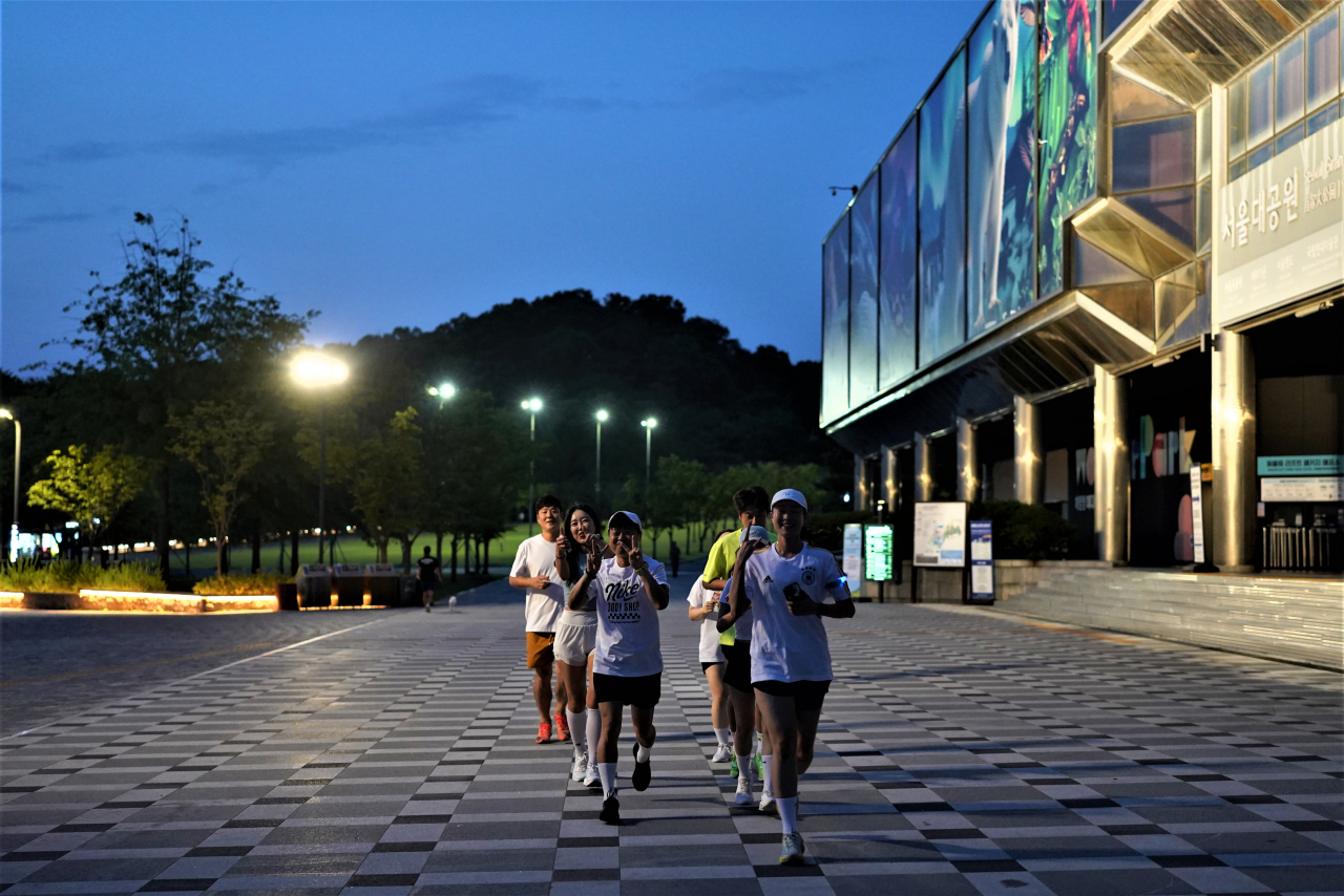 Seoul Ddimbak members pose for photos while running along the trail at Seoul Grand Park in Gwacheon, Gyeonggi Province, on June 12. (Lee Si-jin/The Korea Herald)