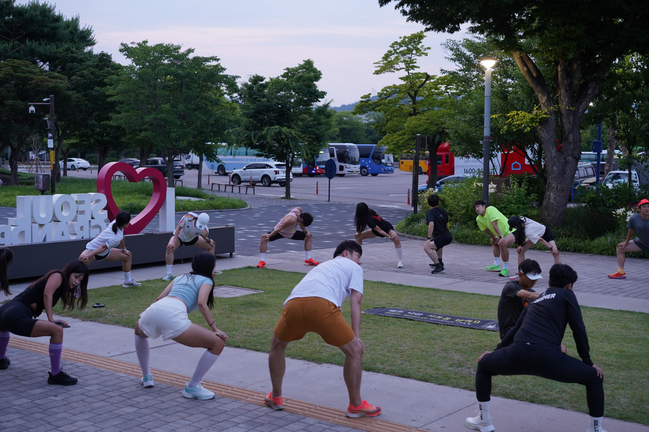 Seoul Ddimbak members warm up before starting on a regular run at Seoul Grand Park in Gwacheon, Gyeonggi Province, on June 12. (Lee Si-jin/The Korea Herald)